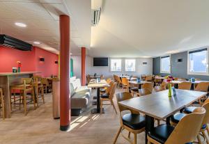 un restaurant avec des tables et des chaises en bois et des murs rouges dans l'établissement B&B HOTEL Colmar Lumière, à Colmar