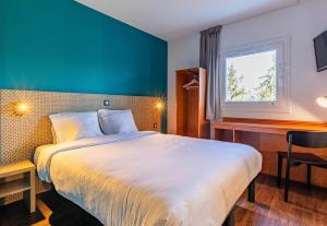 コルマールにあるB&B HOTEL Colmar Lumièreのベッドと机と窓のある寝室