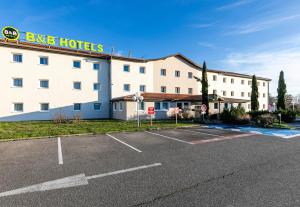 ein Hotel mit Parkplatz davor in der Unterkunft B&B HOTEL Colmar Lumière in Colmar