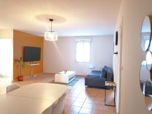 a living room with a couch and a tv at Hôtel Restaurant Platanes - KB HOTEL GROUP in Étauliers