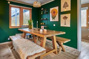 a dining room with a wooden table and green walls at Cosy cabin w fireplace 3 mins from Söderåsen Park in Ljungbyhed
