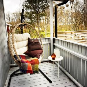 a wicker chair sitting on a porch with a table at Cosy cabin w fireplace 3 mins from Söderåsen Park in Ljungbyhed