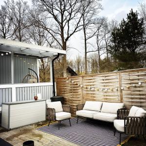 a patio with white chairs and a fence at Cosy cabin w fireplace 3 mins from Söderåsen Park in Ljungbyhed