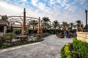 un patio con sillas, mesas y palmeras en Babylon Rotana Hotel, en Baghdād
