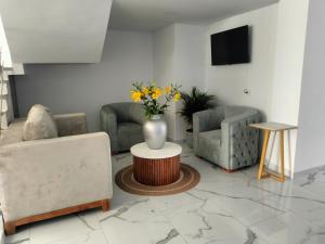 a living room with two chairs and a vase of flowers on a table at HOTEL CALIFORNIA in Pitalito