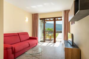 een woonkamer met een rode bank en een glazen tafel bij Residence Dany appartamenti con cucina vista lago piscina e parcheggio in Gargnano