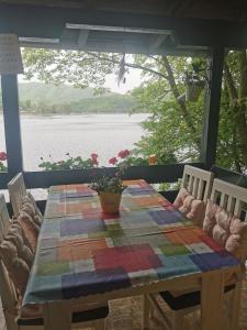 a table with a quilt on it with a view of the water at Kućica na Jezeru Ovčarsko-kablarska klisura Boat Access Only in Čačak +24 photos