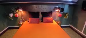 una camera da letto con letto arancione e cuscini rossi di L'usine à rêves a Saint-Germain-du-Corbéis