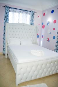 a white bed in a room with polka dots on the wall at Kerith Springs Family Holiday home Bamburi Msa in Bamburi