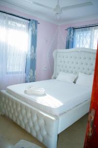a large white bed in a room with blue curtains at Kerith Springs Family Holiday home Bamburi Msa in Bamburi