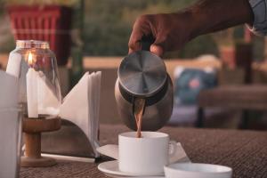 a person pouring coffee into a cup on a table at Explore Hostel Life Jaisalmer in Jaisalmer