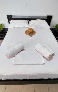 Una cama blanca con dos toallas y un sombrero. en ΚΟΡΩΝΙΔΑ, en Ligourio