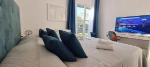 sypialnia z łóżkiem z niebieskimi poduszkami i telewizorem w obiekcie Villa Gisira - Luxury SPA w mieście Brucoli