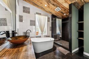baño con bañera grande y techo de madera en Cozy, luminous and charming retreat, en Harrington