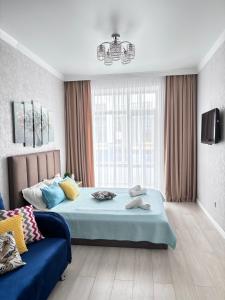 1 dormitorio con 1 cama azul y 1 sofá azul en ЖК ALPAMYS, en Astana