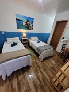 two beds in a room with blue walls and wooden floors at Batera House Noronha in Fernando de Noronha