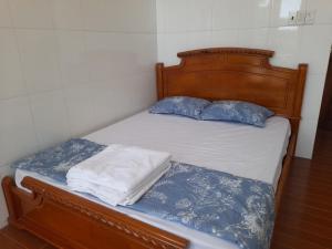 Bett mit blauer und weißer Bettwäsche und blauen Kissen in der Unterkunft NGỌC LINH MT in Trung An