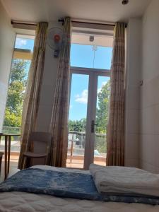 a bedroom with a bed and a large window at NGỌC LINH MT in Trung An