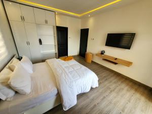 - une chambre avec un lit blanc et une télévision à écran plat dans l'établissement Star tower, à Accra