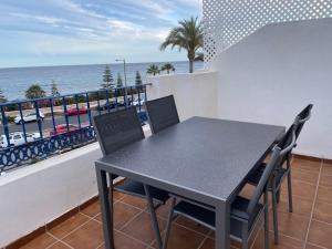 a black table and chairs on a balcony with the ocean at mirazul mojacar in Mojácar