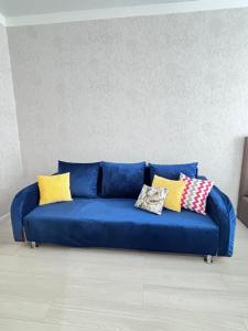 un sofá azul con almohadas en una habitación en ЖК ALPAMYS, en Astana