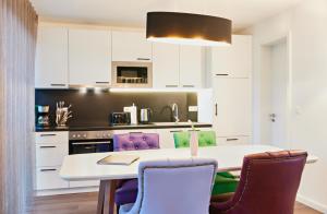 a kitchen with a white table and purple chairs at Bernsteinland in Wendorf