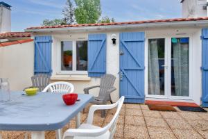 einen blauen Tisch und Stühle auf einer Terrasse mit einem Haus in der Unterkunft Séjour calme dans une maison avec jardin in Saint-Maixent-sur-Vie