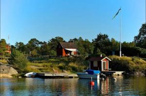 a small house and a boat on a body of water at Cabin retreat in the archipelago in Djurhamn
