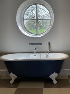 a bath tub in a bathroom with a round window at Swan Farm in Daventry +6 photos