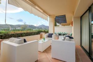 a balcony with white wicker furniture and a view of the mountains at 2-bed apt in Capanes del Golf in Benahavís