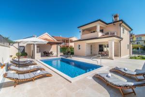 a villa with a swimming pool and patio furniture at Vila Orchidee in Poreč