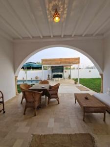 eine Terrasse mit einem Tisch, Stühlen und einem Sofa in der Unterkunft Dar Douja à Chaffar / Ton chez-toi près de la plage in Nakta