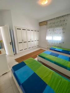 - une chambre avec 2 lits et des tons blancs et bleus dans l'établissement Dar Douja à Chaffar / Ton chez-toi près de la plage, à Nakta