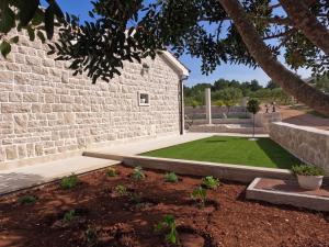um jardim com um relvado ao lado de uma parede de tijolos em Villa Maginja em Sutivan