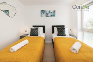 2 camas en una habitación con sábanas amarillas y toallas en Modern 2 Bedroom Retreat, en Kent