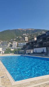 a large blue swimming pool with buildings in the background at Blue Horizon 1 in Vlorë