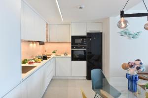a kitchen with white cabinets and a black refrigerator at El Balcon Azul de Taliarte by VillaGranCanaria in Telde