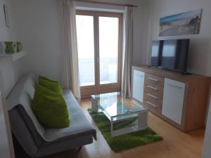 sala de estar con sofá, TV y mesa de cristal en Ferienwohnung Schnell en Flachau