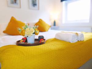 a yellow bed with a tray with towels and flowers on it at Luxury 2 Bed, 2 Bath Apartment in Central Watford in Watford