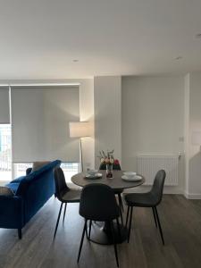 a dining room with a table and chairs and a blue couch at Brand New Stunning 2-Bed Apartment in Dagenham in Dagenham