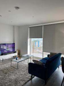 ein Wohnzimmer mit einem blauen Sofa und einem TV in der Unterkunft Brand New Stunning 2-Bed Apartment in Dagenham in Dagenham