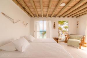 a white bedroom with a bed and a chair at Casa Tinti Hotel Boutique in Tintipan Island