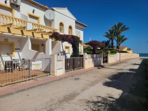 ein Haus mit einem Zaun am Meer in der Unterkunft Bungalow PUEBLO MAR en Els Poblets. in Denia