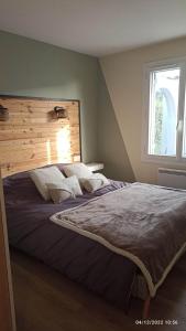 a bedroom with a large bed with a wooden headboard at CHEZ AURELIE MAISON T4 90m2 CONVIVIALE AU COEUR DES VIGNES ET CHATEAUX in Parempuyre
