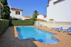 une piscine avec deux chaises bleues et une maison dans l'établissement Bungalow PUEBLO MAR en Els Poblets., à Dénia