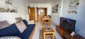 ein Wohnzimmer mit einem blauen Sofa und einem TV in der Unterkunft Apartamento Sunrise in Altura