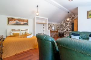 a bedroom with a bed and two green leather chairs at Gerês Escape Retreat - Casa da Fonte de Pedra in Vieira do Minho