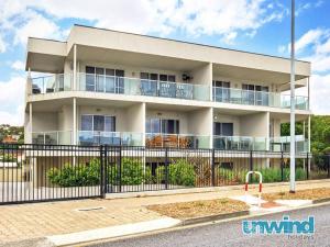 a white building with a fence in front of it at Block Escape - Ocean View Apartment No 1 in Victor Harbor