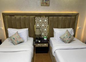 2 łóżka w pokoju hotelowym z białymi poduszkami w obiekcie Royal Golden Pyramids Inn w Kairze