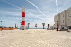 a red and white lighthouse next to a building at Apartamento playa del Carmen in Barbate